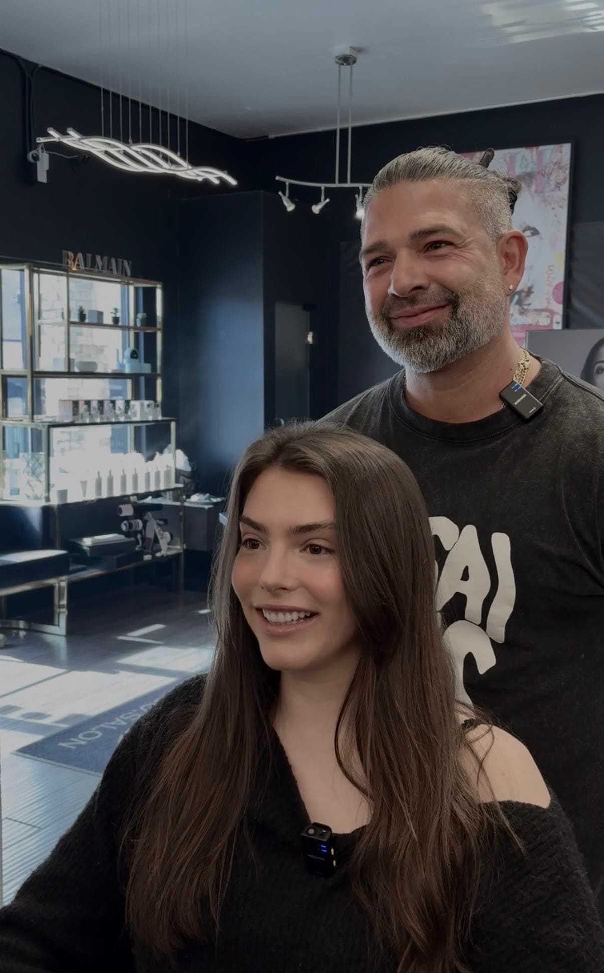 Man styles woman's hair in modern salon setting.