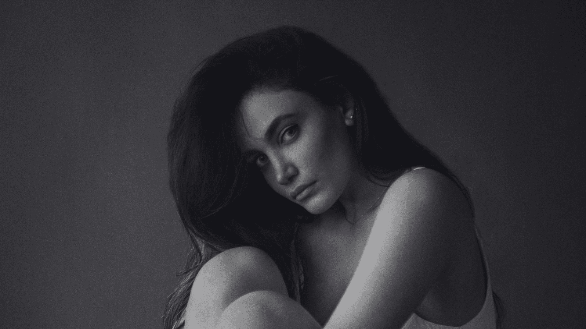 Female model seated, gazing thoughtfully in monochrome portrait.